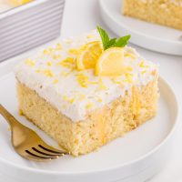 slice of lemon curd cake with a fork on white plate